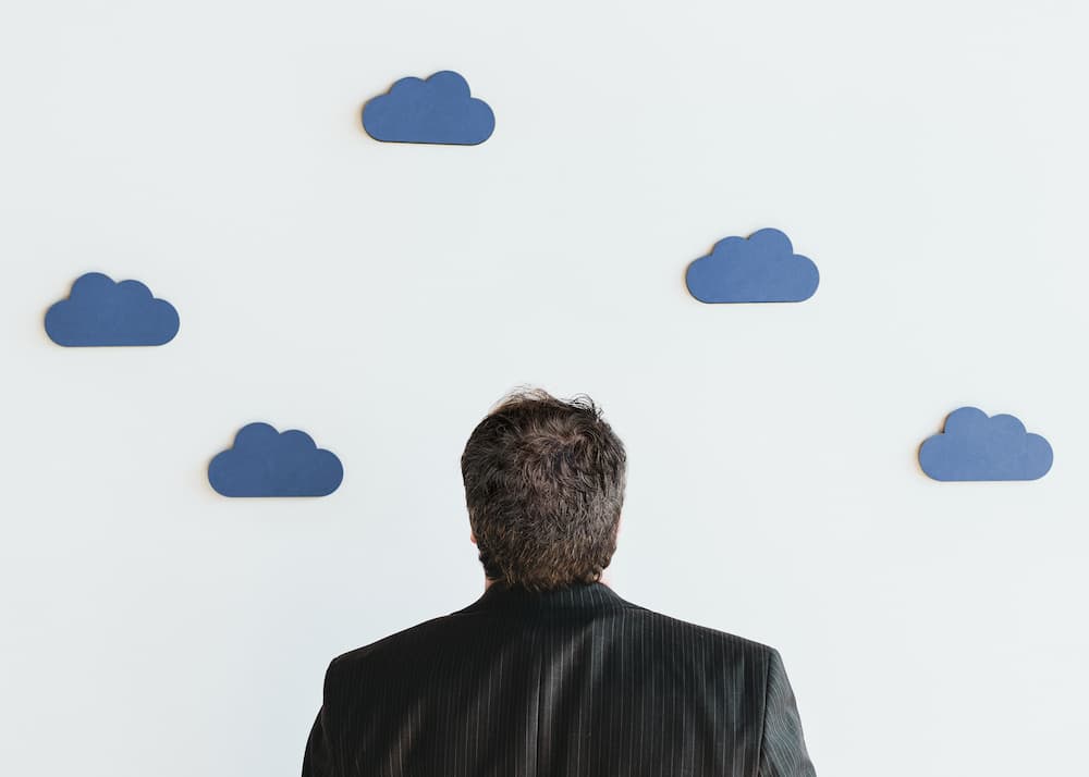 man looking at paper clouds