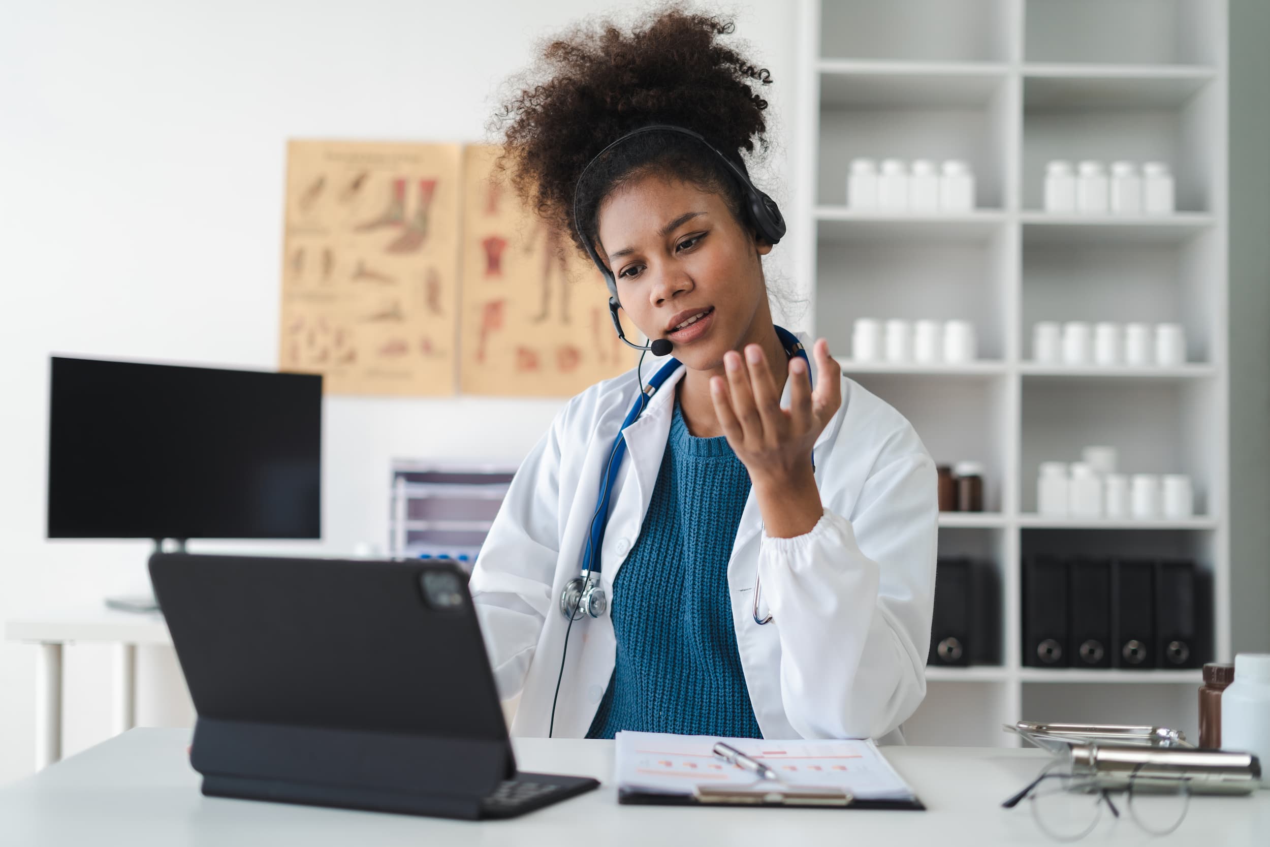 Doctor providing online consultation during a virtual appointment, looking at her hand and speaking with concern