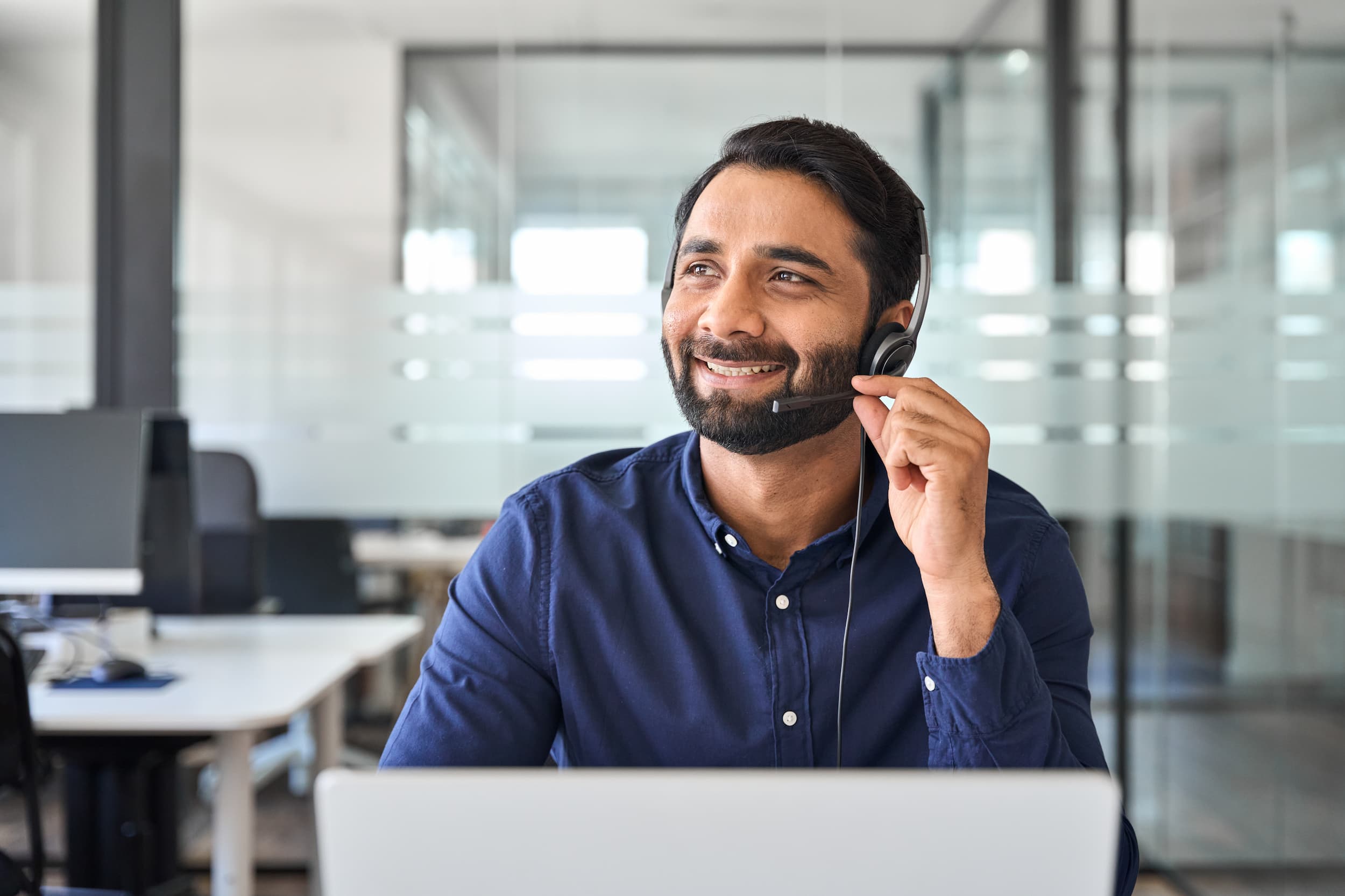 Smiling male support agent wearing a headset providing customer assistance from a modern office